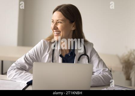 Lächelnde Therapeutin, die im Krankenhaus am Laptop arbeitet Stockfoto