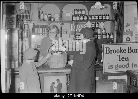 Naher Osten Sergeanten Frau Einweisende's Job-Leben Als Eisenbahn Signalwoman, Molland, Devon, England, UK, 1943 Jetzt dienstfrei, Signalwoman Daisy Kochen und ihre acht Jahre alte Tochter das Dorf stores Bishops Nympton besuchen Ihre Rationen zu sammeln. Stockfoto