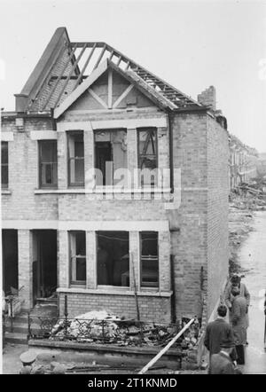 Morrison Zuflucht auf Trial-Test der neuen Indoor Tierheim, 1941 Männer, vermutlich aus dem Ministerium für Sicherheit zu Hause prüfen, die innerhalb und außerhalb des Hauses in diesem Test einer Indoor Tisch - verwendet werden Typ Luftschutzbunker, irgendwo in Großbritannien im Jahr 1941. Es scheint, dass dieses Haus und die Umgebung schon bei einem Luftangriff schwer beschädigt. Stockfoto