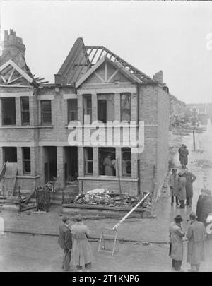 Morrison Zuflucht auf Trial-Test der neuen Indoor Tierheim, 1941 Männer, vermutlich aus dem Ministerium für Sicherheit zu Hause prüfen, die innerhalb und außerhalb des Hauses in diesem Test einer Indoor Tisch - verwendet werden Typ Luftschutzbunker, irgendwo in Großbritannien im Jahr 1941. Es scheint, dass dieses Haus und die Umgebung schon bei einem Luftangriff schwer beschädigt. Stockfoto