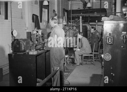 National Physical Laboratory - Wissenschaft und Technologie in Kriegszeiten, Teddington, Middlesex, England, Großbritannien, 1944 eine Szene, in der Forschungsabteilung des National Physical Laboratory, Teddington, Wissenschaftler, die an der Arbeit untersucht die Wirkung der Kräfte auf ein Modell Propeller. Der Fahrer in der Mitte sitzt auf der Suche durch das Sichtfenster des oberen Arms der Lithgow druck Tunnel. Die Ursprüngliche Bildunterschrift heißt es, dass das Wasser in diesem Abschnitt der Kreislauf in Bewegung ist mit geregelter Geschwindigkeit und unter kontrolliertem Druck. Der Propeller im Test ist angeschlossen Stockfoto