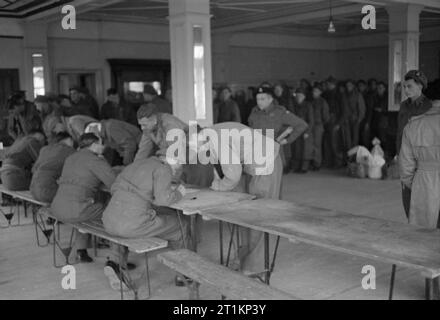 Neuseeland Aussiedler in England ankommen - den Alltag für die Heimschaffung der Kriegsgefangenen in Ramsgate, Kent, England, UK, April 1945 Mitarbeiter nehmen die Angaben der Neuankömmlinge an der Rezeption Zentrum für befreite Neuseeland Kriegsgefangene, im Grand Hotel, Westcliff, Margate. Ein Kabel mit ihren Familien in Neuseeland geschickt, in der es über die sichere Ankunft in England zu informieren. Gemäß der ursprünglichen Bildunterschrift, "die Männer sind jedem erlaubt, 2 freie Kabel home nach Neuseeland" zu senden. Stockfoto