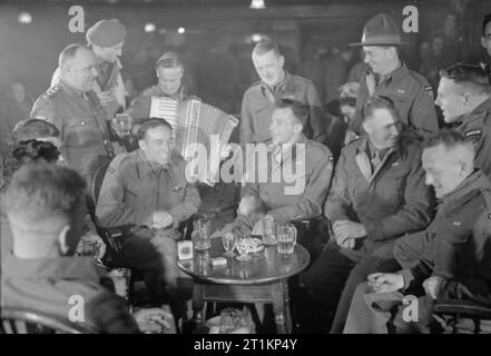 Neuseeland Aussiedler in England ankommen - den Alltag für die Heimschaffung der Kriegsgefangenen in Ramsgate, Kent, England, UK, April 1945 Neu repatriiert Neuseeland Kriegsgefangenen teilen ein Witz, da sie ein Pint Bier in einem Pub in Ramsgate, Kent genießen. Einer ihrer Zahl spielt das Akkordeon. Stockfoto