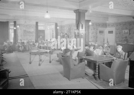 Neuseeland Aussiedler in England ankommen - den Alltag für die Heimschaffung der Kriegsgefangenen in Ramsgate, Kent, England, UK, April 1945 einen Überblick über die übrigen Zimmer, oder in der Lounge, im Norfolk Hotel, Westcliff, Margate. Neu - Repatriiert Neuseeland Kriegsgefangenen entspannen und die Zeitung in der komfortablen Umgebung lesen. Stockfoto