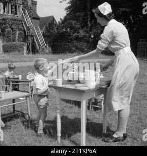 Kindergarten - Leben im alten Herrenhaus, Wendover, Buckinghamshire, England, 1944 ein Junge sammelt seine Pudding von der Krankenschwester, als sie Mittagessen im sonnigen Garten des Kindergarten im alten Herrenhaus in Wendover dient. Die Legende besagt, dass, wo immer möglich, mit den Kindern die Mahlzeiten werden im Freien serviert. Stockfoto