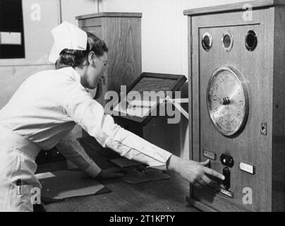 Radium Behandlung in einem Krankenhaus in London, England, 1940 eine Krankenschwester Schalter auf dem radium Behandlung Apparate in einem Londoner Krankenhaus im Jahre 1940. Wenn der Patient bereit ist, und alle anderen die Behandlung Zimmer, die Krankenschwester drückt eine Taste und Luftdruck einmal mehr überträgt die Radium aus der Leitung sicheres für die Behandlung Apparate nach links. Stockfoto