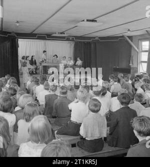 Schule für Umsiedler - Alltag an der Marchant Hill Camp Schule, Hindhead, Surrey, England, UK, 1944 Während einer Schulversammlung an Marchant Hill's School, Hindhead, schulsprecher Vic Randall (Alter 14) stellt, um einen Lautsprecher an das Publikum. Die Kinder sind in einem der großen Hütten versammelt (ein Satz wie ein Aula) Welche Form alle Unterkünfte und Unterricht in der Schule. Stockfoto