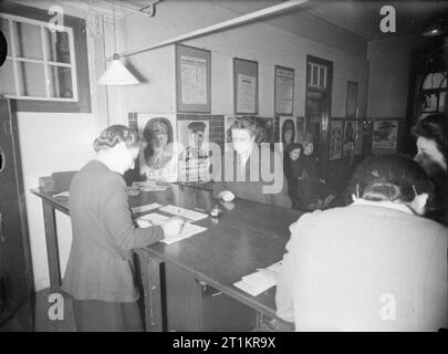 16-jährigen Registrieren - Jugendliche ihre Erwachsenen ID-Karten von der Labour Exchange, London, England, UK, 1945 der 16-jährige Margaret Neal, der Assistent eines Schneiderin, an der Islington Arbeitsamt Register für Ihre erwachsenen Personalausweis. Gemäß der ursprünglichen Caption, Margaret 'verfügt nicht nehmen am Abend, als sie in eine Jugendorganisation gehören, und so wird später von der Jugend Behörden befragt werden. Hinter ihr kann viele Rekrutierung Poster gesehen werden. Stockfoto