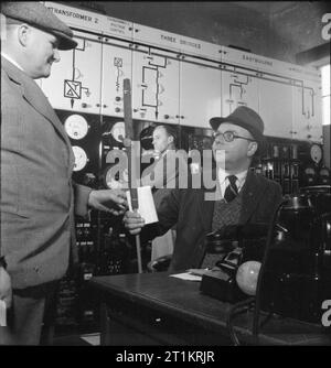 Die britische Grid System - die Arbeit der Central Electricity Board in Kriegszeiten, c März 1945 Herr J Kelly, Vorarbeiter einer Reparatur und Wartung Schleifring, nimmt eines Arbeitsfreigabesystems Karte und eine farbige Markierung (die bezeichnet, welcher Kreislauf er wird sich) aus dem Abschnitt Engineer bei einem Strom Station, wahrscheinlich in Sussex. Wartung Mannschaften haben in der großen Nachfrage während des Krieges gewesen war, Instandsetzung von Stromleitungen, die von feindlichen Angriff beschädigt wurden, sondern auch durch anti-aircraft Feuer und Kampf üben. Gemäß der ursprünglichen CAPTION,'Sobald eine Störung auftritt eine Patrouille erlischt, lokalisiert sie neu an. Stockfoto