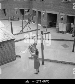 Die Cottages von Freefolk - Leben im Dorf Freefolk, Hampshire, England, Großbritannien, 1943 eine Frau heraus hängt ihre Wäsche in den Hinterhof von ihrem Häuschen in Freefolk, Hampshire. Jedes Cottage hat einen Gemüse- und Blumengarten vor dem Haus, sondern ein konkretes Yard wurde an der Rückseite der Häuser zur Verfügung gestellt, komplett mit ständigen Wäscheleine Beiträge. Stockfoto