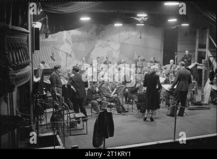 Die Lachen! - die Aufzeichnung der Radio Comedy" itma', London, England, UK, 1945 Charlie Shadwell (rechts) bereitet die BBC Reihe Orchester während der Aufzeichnung einer Episode von "Es ist, dass der Mensch wieder durchzuführen. Zu seiner Linken ist Ann reichen, die 'ITMA'Sängerin Paula Grün gelungen. Auf der linken Seite des Fotos, Produzent Francis Worsley Chats zu Sender Ronnie Waldman. Stockfoto