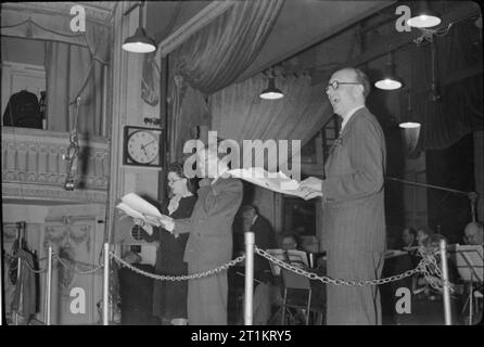 Die Lachen! - die Aufzeichnung der Radio Comedy" itma', London, England, UK, 1945 Dirigent Charlie Shadwell (rechts) lacht bei Tommy Handley und Dorothy Sommer während der Aufzeichnung einer Episode von "Es ist, dass der Mensch wieder'. Die BBC Reihe Orchester hinter ihnen sichtbar auf der Bühne. Stockfoto