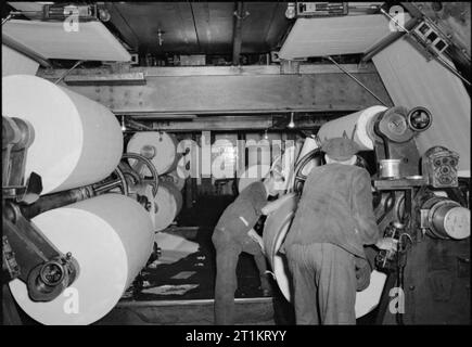 Die Voraussetzungen Eines modernen Zeitung - die Produktion der "Daily Mail" in Kriegszeiten, London, UK, 1944 Zeitung Mitarbeiter beenden Einlegen von Papier in den großen Rollen der Druckmaschine in der Haspel Zimmer der Zeitung Büros. Gemäß der ursprünglichen Bildunterschrift, die Rollen sind so platziert, dass sie während der 'Lauf' kann ohne Anhalten der Pressen". Stockfoto