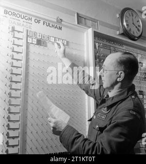 Die Rekonstruktion der 'Vorfall' - Zivilschutz Ausbildung in Fulham, London, 1942 Die Sekretärin-zu-Einsatzleiter des Control Center stellen Registerkarten aus der Systemsteuerung auf den Vorfall. Diese Registerkarten repräsentieren Dienstleistungen entweder an oder auf dem Weg zu, den Vorfall. Stockfoto