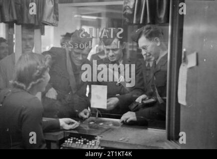 Amerikaner in Großbritannien - die Ankunft der Zivilen technischen Korps, Bournemouth, England, 1941 Manning, Henning und Shapiro der Zivilen technischen Korps Tickets kaufen im Kino in Bournemouth. Das Foto ist von der Innenseite der Karte stand genommen und eine Warteschlange kann gesehen werden, die hinter ihnen. Die Männer sind ursprünglich von Del Rio, Texas, Champaign, Illinois und Chicago. Stockfoto