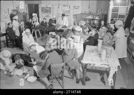 Die Rekonstruktion der 'Vorfall' - Zivilschutz Ausbildung in Fulham, London, 1942 eine belebte Szene in der Behandlung Raum der Ersten, bis in einem Zimmer in einem der Schule eingestellt, wahrscheinlich Mary Boon Schule, an der Ecke der Straße und Earsby Bishop's King's Road, in der Nähe der Avonmore Road. Krankenschwestern behandeln verschiedene Verletzungen, einschließlich das verletzte Bein eines Jungen. Im Hintergrund, der Arzt und der Betriebsleiter Krankenschwester kümmern sich um einen Mann mit einer Verletzung zurück. Eine Reihe von Postern an der Wand können gesehen werden, ermutigen die Menschen den Krieg in vielfältiger Weise zu unterstützen. Stockfoto