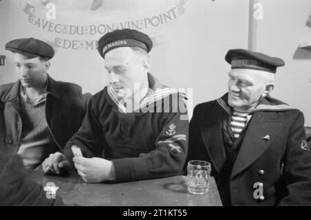 Die sieben Meere Verein - Leben im Merchant Marine Club, Edinburgh, Schottland, 1943 Olaf Tier, ein Matrose aus Norwegen, bereitet seine Hand in ein Kartenspiel in der Bar der Sieben Meere Club in Edinburgh zu spielen. Er ist beobachtet von J Craamer aus Holland (rechts). Auf der linken Seite des Fotos kann Paul Grossman aus New York, die auch in der Karte Spiel beteiligt ist, gesehen werden. Stockfoto