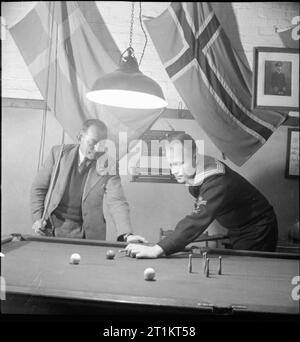 The Seven Seas Club - Life im Merchant Navy Club, Edinburgh, Schottland, 1943 Olaf Christensen (links) aus Dänemark und Olaf Lien, ein Seemann aus Norwegen, spielen im Seven Seas Club in Edinburgh eine Partie Billard. Darüber befinden sich die Flaggen zweier Länder, deren Bürger diesen Club befördern. Stockfoto