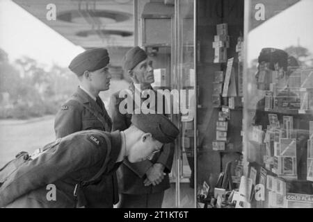 Amerikaner in Großbritannien - die Ankunft der Zivilen technischen Korps, Bournemouth, England, 1941 Männer der Zivilen technischen Korps Blick auf Waren, die in das Fenster eines tobacconist Shop in Bournemouth. Nach vorne beugen ist Henning, ursprünglich aus Champaign, Illinois, und seine Kollegen sind Shapiro (Chicago) und Manning (von Del Rio, Texas). Stockfoto