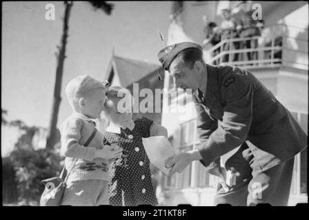 Amerikaner in Großbritannien - die Ankunft der Zivilen technischen Korps, Bournemouth, England, 1941 J E Beardwood der Zivilen technischen Korps bietet Spezialitäten zu einem Jungen und Mädchen auf einer sonnigen Bournemouth Straße. Beardwood ist ursprünglich aus Brooklyn, New York, und hat eine Frau und zwei Töchter zurück in den Vereinigten Staaten. Stockfoto