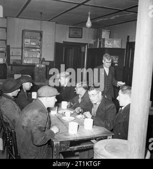 Sie Fahren bei Nacht - die Arbeit der Fernfahrer in Kriegszeiten, England, UK, 1944 LKW-Fahrer Fred Horrod (Mitte hinten) Sitzt unter anderen Fernfahrer ein spätes Abendessen um Mitternacht zu genießen, wie er seine Reise von London bricht nach Manchester. Er reist seit etwa 8 Uhr. Die Ursprüngliche Bildunterschrift heißt es: "Vor dem Krieg Eier und Speck, Eier und Pommes und kalten Schinken, Würstchen, Pommes und Sandwiches mit Käse oder Spam gegeben haben. Wenn Rationierung war Cafés der LKW-Fahrer' für eine Zeit begann, ging sehr kurze, aber die Dinge sind jetzt besser. Hot süßer Tee ist t Stockfoto