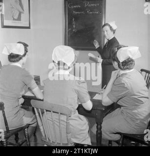 Ausbildung der Königin Krankenschwestern - Bezirk Krankenschwester Ausbildung im Queen's Institut für Bezirk Krankenpflege, Guildford, Surrey, England, UK, 1944 Auszubildende zu einem Vortrag von einer Schwester im Queen's Institut für Bezirk Krankenpflege in Guildford anhören. Nach dem Schreiben an der Tafel, das Thema ist "Allgemeine District Nursing Routine". Stockfoto