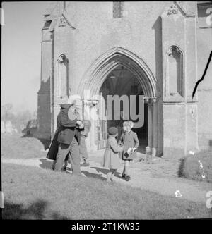 Dorfkirche - Alltag in Uffington, Berkshire, England, UK, 1944 Mitglieder der Gemeinde, darunter zwei Jungen, in die Sonne, wie Sie die Kirche St. Maria, der Jungfrau, Uffington, Berkshire, folgenden Sonntag morgen Service verlassen. Stockfoto