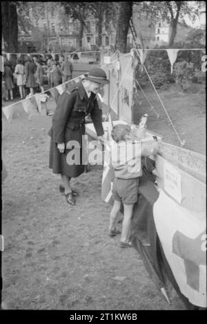 Krieg Fair - Urlaub zu Hause auf einer Fete in Russell Square, London, 1943 Mitglied des Roten Kreuzes betreut als Junge versucht, einen Nagel in den Sarg am Russell Square fete zu fahren. Nach dem ursprünglichen Titel, Ziel war es, den Nagel in innerhalb von drei Schläge zu erhalten, obwohl junge Kinder einen Vorsprung gegeben wurden! Stockfoto