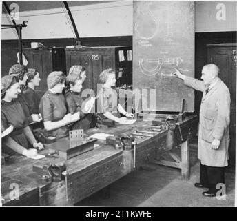 Women's Factory Krieg Arbeit in Slough Training Center, England, Großbritannien, 1941 eine Gruppe von Frauen in Slough Training Center hören Sie einen Vortrag in einem Workshop. Auf der Tafel, Diagramme von außen, innen Bremssättel Bremssättel und einem Mikrometer werden aufgezeigt und erklärt. Stockfoto