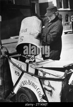 Frauen Straßenreinigung Brigade - Weibliche müllmännern am Arbeitsplatz, London, 1942 Mitglied der St Pancras von Frauen Straßenreinigung Brigade leert ein Schwein bin in die bergung Abschnitt ihres Staub Barrow. Dieses Foto zeigt deutlich, dass die Trennung zwischen den beiden Bereichen auf der Staub Warenkorb: eine für allgemeine Müll und eine für die Bergung. Stockfoto