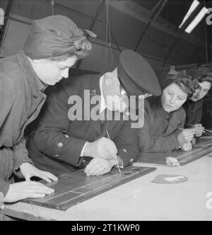 Zaunkönige Zug für neuen Job-Training für Schiffsmechaniker der Royal Naval der Frauen Service, England, UK, 1943, die in der Lackierwerkstatt einer Regierung, Training Center, wahrscheinlich Slough, a naval Chief Petty Officer Ausbilder unterrichtet Zeichen schreiben zu einer Gruppe von Frauen der WRNS. Die Frauen sind die Ausbildung zum Schiffsmechaniker (LC) und diese Zeichen schreiben Fähigkeiten wird für die Malerei die Identifizierungsnummern auf Landing Craft benötigt werden. Stockfoto