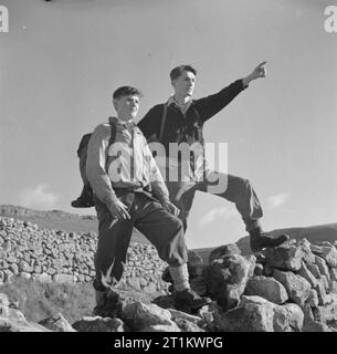 Junge Wanderer in Yorkshire - die Arbeit der Youth Hostel Association in Wartime, Malham, Yorkshire, England, Vereinigtes Königreich, 1944 zwei Jungs halten bei einem Spaziergang durch die Landschaft Yorkshires in der Sonne inne, um die Aussicht zu bewundern, einer von ihnen weist auf etwas in der Ferne hin. Sie haben ihren Spaziergang von einer Jugendherberge aus begonnen, wahrscheinlich in Malham. Stockfoto