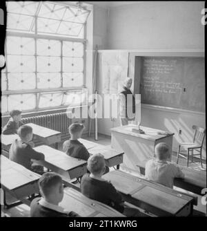 Junge Briten studieren amerikanische Geschichte- Bildung in Kriegszeit England, 1943 Jungen an der Albany Senior School sitzen leise und hören zu, wie ihr Lehrer Mr. A B Culwell ihnen eine Lektion über Amerika und den Spanisch-Amerikanischen Krieg gibt. Laut der Originalüberschrift war Mr. Culwell einst Schulmeister der Royal Navy und besuchte viele amerikanische Häfen und Städte. Achten Sie auf das durchkreuzte Klebeband an den Fenstern, um Beschädigungen durch Explosionen zu vermeiden. Stockfoto