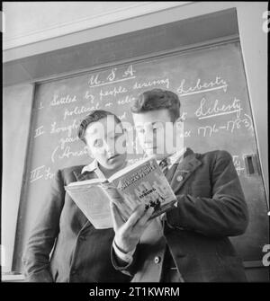 Junge Briten studieren American History – Education in Wartime England, 1943 Ronald Wale (links) und Ronald Prior stehen vor der Tafel und lesen eine Kopie des Buches „Story of the American People“ von C F Strong während eines Unterrichts über Amerika an der Albany Senior School. Stockfoto