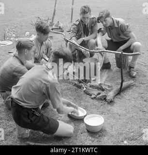 Jugendtreffen- Wohnausbildung Für Jugendorganisationen, Sidcot School, Winscombe, Somerset, England, Großbritannien, 1943 im Rahmen eines einwöchigen Jugendtrainings, der an der Sidcot School in Somerset abgehalten wird, machen fünf Pfadfinder bei einem Lagerfeuer Brot. Im Vordergrund macht ein Scout den Teig, während hinter ihm ein anderer die dampfende billy Can über dem Lagerfeuer aufrührt. Stockfoto