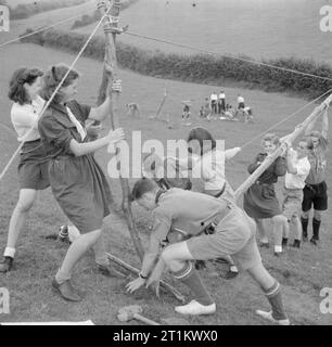 Jugendversammlungen - Ausbildung Für Jugendorganisationen, Sidcot School, Winscombe, Somerset, England, Großbritannien, 1943 Girl Guides und Boy Scouts arbeiten zusammen, um eine Seilbrücke während eines Kurses in Camping und Holzarbeit im Rahmen des einwöchigen Jugendtrainings an der Sidcot School in Somerset zu bauen. Stockfoto