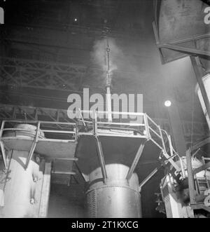 Geburt einer Waffe - die Produktion einer 25 Pounder Field Gun, 1942 eine wichtige Rolle in der Produktion des 25 pounder Gun ist die Härten und Anlassen. Nach der Bearbeitung fahren die Gun Barrel wird auf eine festgelegte Temperatur für das Härten in einem vertikalen elektrischen Ofen beheizt. Es ist dann zurückgezogen und in ein ölhärtebad nach dem es gemildert wird abgesenkt. Dieses Foto zeigt den Lauf langsam in das Abschreckbad abgesenkt wird. Stockfoto