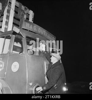 Ein Fernfahrer der Reinigung der Windschutzscheibe seines 7-Tonne Leyland Lkw vor seiner Reise Wiederaufnahme im Jahr 1944. Nach dem Essen eine 24.00 Uhr Abendessen im Mai Cafe, (ein LKW-Fahrer" "pull-up" irgendwo zwischen London und Manchester), Fred Horrod reinigt die Frontscheibe seines 7-Tonne Leyland Lkw bevor er seine Reise fortsetzen. Die Legende besagt, dass er nicht wieder aufhören, bis er Manchester erreicht. Stockfoto