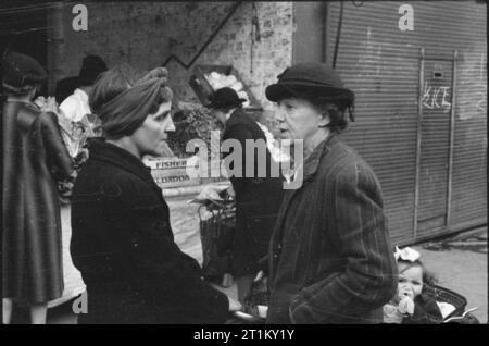 Großbritannien Warteschlangen für Lebensmittel - Kontingentierung und Nahrungsmittelknappheit in Kriegszeiten, London, England, UK, 1945 zwei Hausfrauen das Problem der Lebensmittelknappheit während einem Shopping Trip zu besprechen, irgendwo in London. Stockfoto