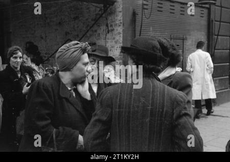 Großbritannien Warteschlangen für Lebensmittel - Kontingentierung und Nahrungsmittelknappheit in Kriegszeiten, London, England, UK, 1945 eine Gruppe von Hausfrauen, die das Problem der Lebensmittelknappheit während einem Shopping Trip zu besprechen, irgendwo in London. Stockfoto