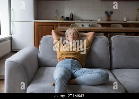 Friedliche Frau, die mit geschlossenen Augen auf einer bequemen Couch ruht Stockfoto