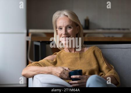 Glückliche ältere Hausbesitzerin, die morgens Kaffee trinkt Stockfoto