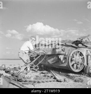 Die britische Armee in Nordafrika 1942 Ein Offizier der Royal Engineers, der die Wrackteile eines deutschen Panzers PzKpfw III überprüft, wurde am 31. Oktober 1942 gesprengt, um zu verhindern, dass der Feind ihn zurückerobert. Er kreidet einen Buchstaben "E" auf der Rückseite des Tanks - "Vernichtung"! Stockfoto