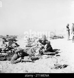 Die Kampagne in Nordafrika 1940-1943 El Alamein 1942: Verwundete britische Soldaten warten auf Bahren für Aufmerksamkeit in einem fortgeschrittenen Dressing Station. Ein Royal Army Medical Corps Officer gibt einen Drink an einer der Verwundeten. Stockfoto