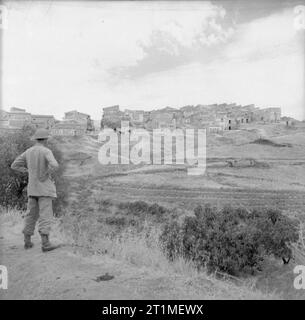 Die Kampagne in Sizilien 1943 die Fahrt nach Messina 10. Juli - 17. August 1943: Ein britischer Soldat Ansichten der Stadt villarosa von einem nahe gelegenen Hügel. Das Wort 'DUCE' wird in großen Buchstaben auf alle Gebäude bemalt. Stockfoto