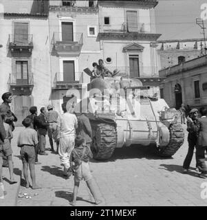 Die Kampagne in Sizilien 1943 die Fahrt nach Messina 10. Juli - 17. August 1943: Ein britischer Sherman Panzer in den Straßen von francofonte. Während der 13. - 14. Juli, XIII Corps, 8. Armee begann eine große Anstrengung Catania zu erreichen. Ihre Bemühungen wurden durch Deutsche Fallschirmjäger in und um Francofonte, die die Britischen voraus für zwei Tage verzögert widerstanden. Stockfoto