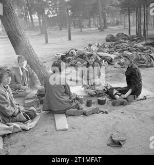 Die Befreiung der Konzentrationslager Bergen Belsen, April 1945 Frauen bereiten Sie eine Mahlzeit in der Nähe der gehäuften Körpern der Toten. Stockfoto