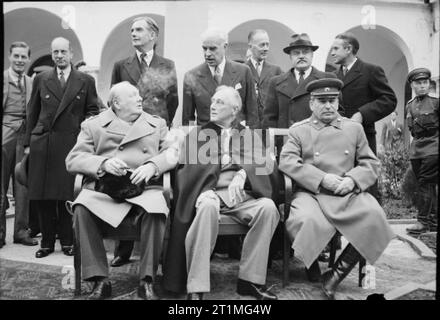 Die Konferenz von Jalta im Februar 1945 die "Großen Drei", Winston Churchill, Präsident Roosevelt und Marschall Stalin, für ein Gruppenfoto vor dem Liwadia-palast während der Konferenz von Jalta sitzen. Dahinter von links nach rechts sind: ein unbekannter Mann; Herr Leder, der britische Minister für Krieg Verkehr; Rt Hon Anthony Eden MP, der britische Minister für Auswärtige Angelegenheiten; Herrn Edward Stettinius, der amerikanische Außenminister; Rt Hon Sir Alexander Cadogan, der britische Staatssekretär für auswärtige Angelegenheiten, Herrn Wjatscheslaw Molotow, der sowjetische Volkskommissar für Auswärtige Angelegenheiten, und Herr Averell Harriman, Stockfoto