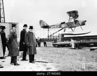 Winston Churchill und des Staatssekretärs für Krieg wartet die Einführung einer De Havilland KÖNIGIN-BIENE funkgesteuerte Ziel drone, um zu sehen, 6. Juni 1941. Die Premierminister Winston Churchill, mit Kapitän das Recht David Margesson, Staatssekretär für Krieg, beobachten die Vorbereitungen in eine unspezifizierte Standort in Großbritannien für die Einführung einer De Havilland KÖNIGIN-BIENE Wasserflugzeug L 5984 von der Rampe. Die KÖNIGIN-BIENE führerlose Ziel drone war eine funkgesteuerte Version der Tiger Moth Trainer. Stockfoto