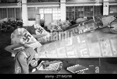 Die Luftwaffe 1939 - 1945 Ein britischer Soldat untersucht in einem Hangar auf dem Flugplatz Wunstorf eine Reihe von teilweise vollständigen Messerschmitt Me 109G Rumpf, gefangen genommen von der 5. Fallschirmbrigade, 6. Airborne Division, 8. April 1945. Die Flugzeuge wurden demontiert und ihre Lackierung als Teil einer nie abgeschlossenen Renovierung gestrichen. Stockfoto